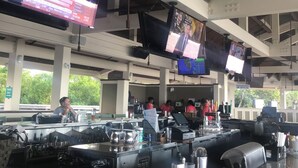 Una terminal aeroportuaria amplia con varias pantallas mostrando noticias e información de vuelos.