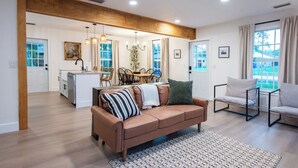A spacious living room with a brown sofa, a patterned rug, and a dining area with wooden chairs and a table. - Vero Beach Gem: Pool, Game Room, King Beds, minutes to the beaches... (Vero Beach)