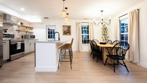 A modern kitchen with a central island, dining area with chairs, and a chandelier. - Vero Beach Gem: Pool, Game Room, King Beds, minutes to the beaches... (Vero Beach)