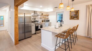 A modern kitchen with stainless steel appliances, a central island with bar stools, and pendant lighting. - Vero Beach Gem: Pool, Game Room, King Beds, minutes to the beaches... (Vero Beach)