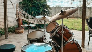 A drum set in an outdoor patio area with a hammock, a brick wall, and a wooden fence in the background. - Rustic Texas Retreat: Ranch style Home Los Ebanitos Ranch  (San Isidro)