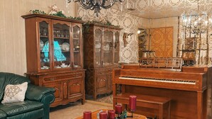 A room with a green leather sofa, wooden cabinets, a grand piano, and a chandelier. - Rustic Texas Retreat: Ranch style Home Los Ebanitos Ranch  (San Isidro)