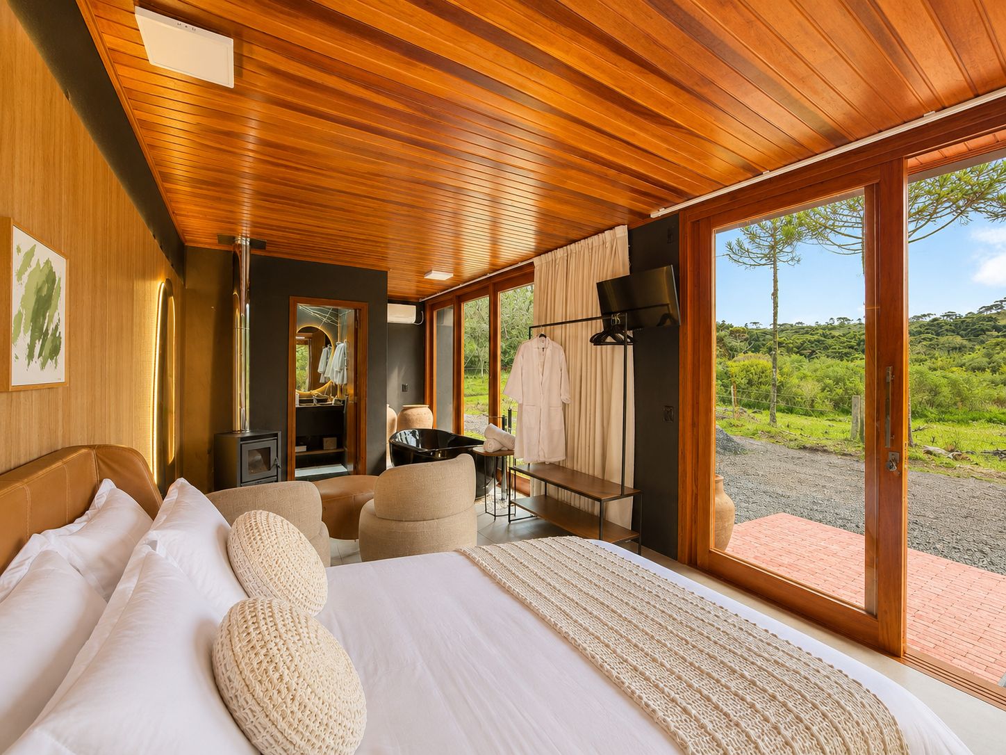 Quarto com cama grande, espaço para sentar e vista para o exterior.