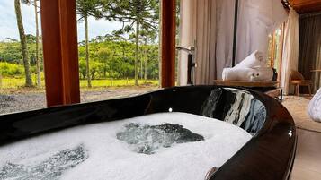 Un jacuzzi con vistas a un paisaje exuberante, vigas de madera y un espacio de descanso acogedor.