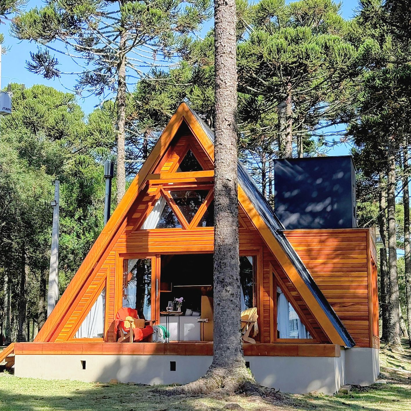 Uma cabana com telhado triangular, fachada de madeira e uma grande janela.