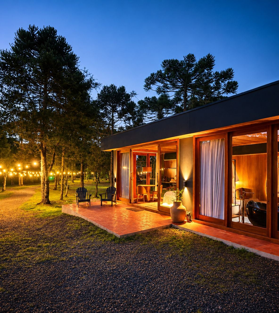 Une maison moderne dotée d’un porche abrité, d’un espace salon extérieur et de guirlandes lumineuses.