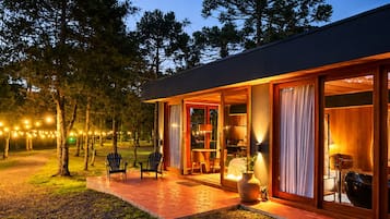 Une maison moderne dotée d’un porche abrité, d’un espace salon extérieur et de guirlandes lumineuses.