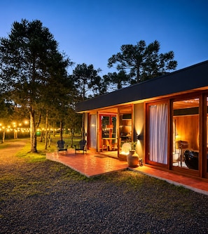 Una casa moderna con porche cubierto, mobiliario exterior e iluminacion con luces colgantes.