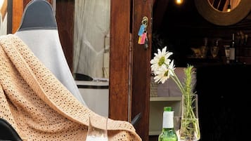 Un rincón acogedor con una mesa preparada para dos, que incluye una botella de cerveza, una copa de vino y un jarrón con flores.