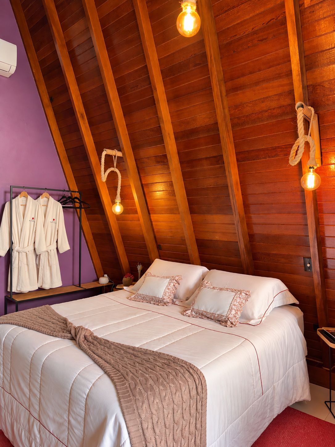 Une chambre avec un plafond en bois, un lit avec une literie blanche et un porte-peignoir avec des peignoirs blancs.