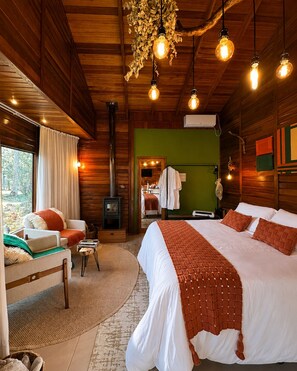 A cozy cabin-style bedroom with a large bed, a fireplace, and a view of the outdoors.