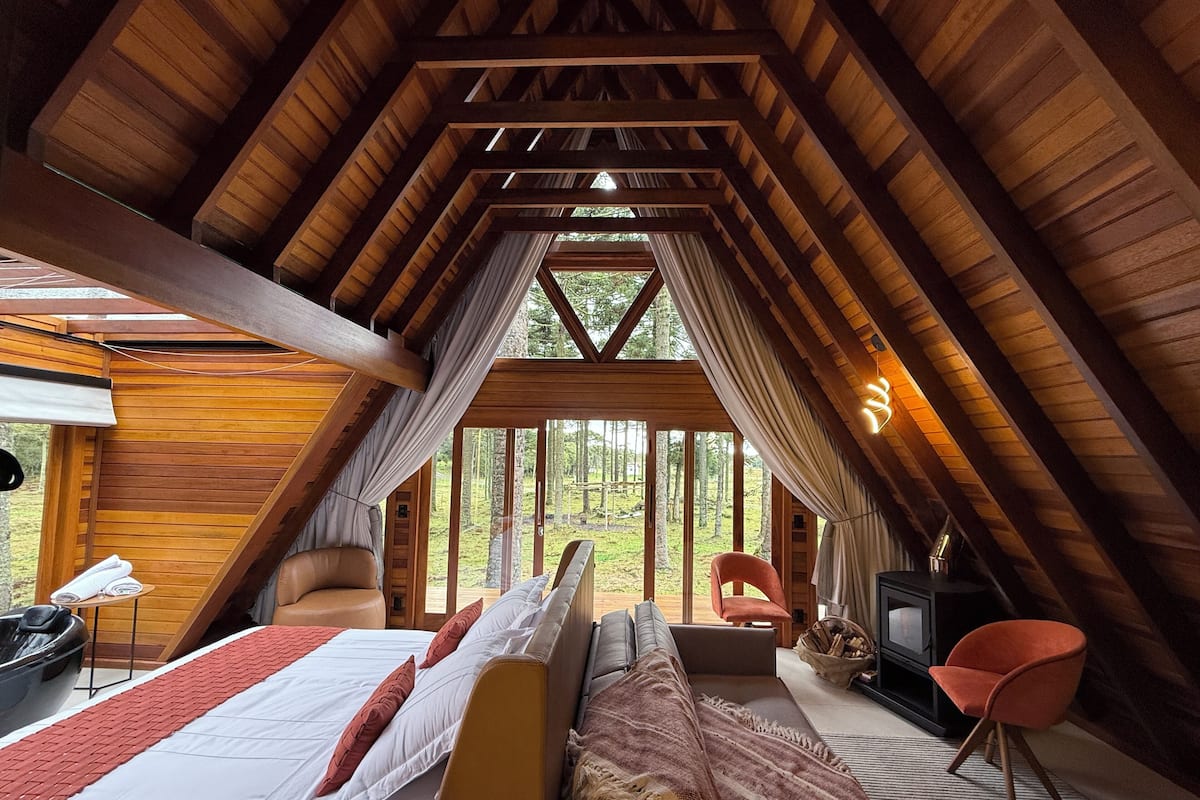 Une chambre confortable située sous les toits, avec un grand lit, un canapé, un fauteuil et une cheminée.