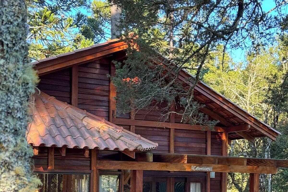 Un chalet rustique doté d’une grande véranda, d’une terrasse en bois et d’un coin repas avec des chaises.
