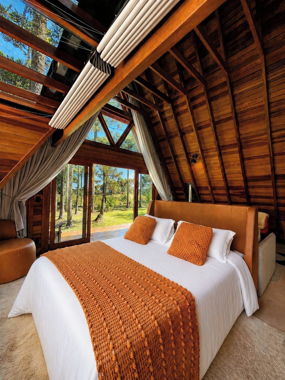 Un dormitorio amplio con una cama grande, vigas de madera y vistas al exterior.
