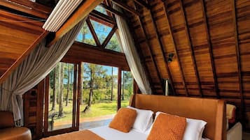 Un dormitorio amplio con una cama grande, vigas de madera y vistas al exterior.