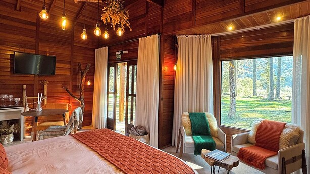 A spacious bedroom with a large bed, a television, and a view of the outdoors. - Pousada Maçã Araucária (São Joaquim)