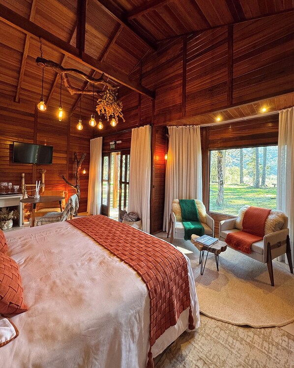 Um quarto espaçoso com uma cama grande, televisão e vista para o exterior.