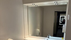 A compact bathroom with a toilet, a sink, and a mirror. - Premier Roomz Two Mills (Ellesmere Port)