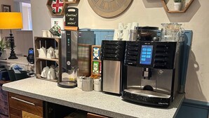 A coffee station with a clock, hexagonal shelves, and a coffee machine. - Premier Roomz Two Mills (Ellesmere Port)