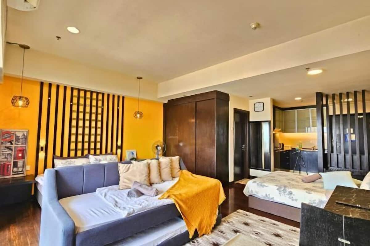 A modern bedroom with a sofa bed, a wooden wardrobe, and a desk with a chair.