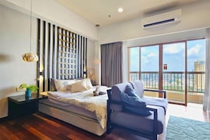 A modern bedroom with a bed, a sofa, a nightstand, a decorative wall panel, and a large window with a balcony view.