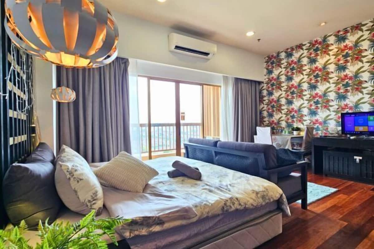 A modern hotel room with a bed, a sofa, a desk, and a balcony.