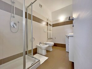 A modern bathroom with a glass-enclosed shower, a toilet, and a bidet. - Cozy Apt With Gym & Parking, Milan (Milan)