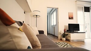 Een moderne woonkamer met een bank, een televisie, een lamp en een potplant.