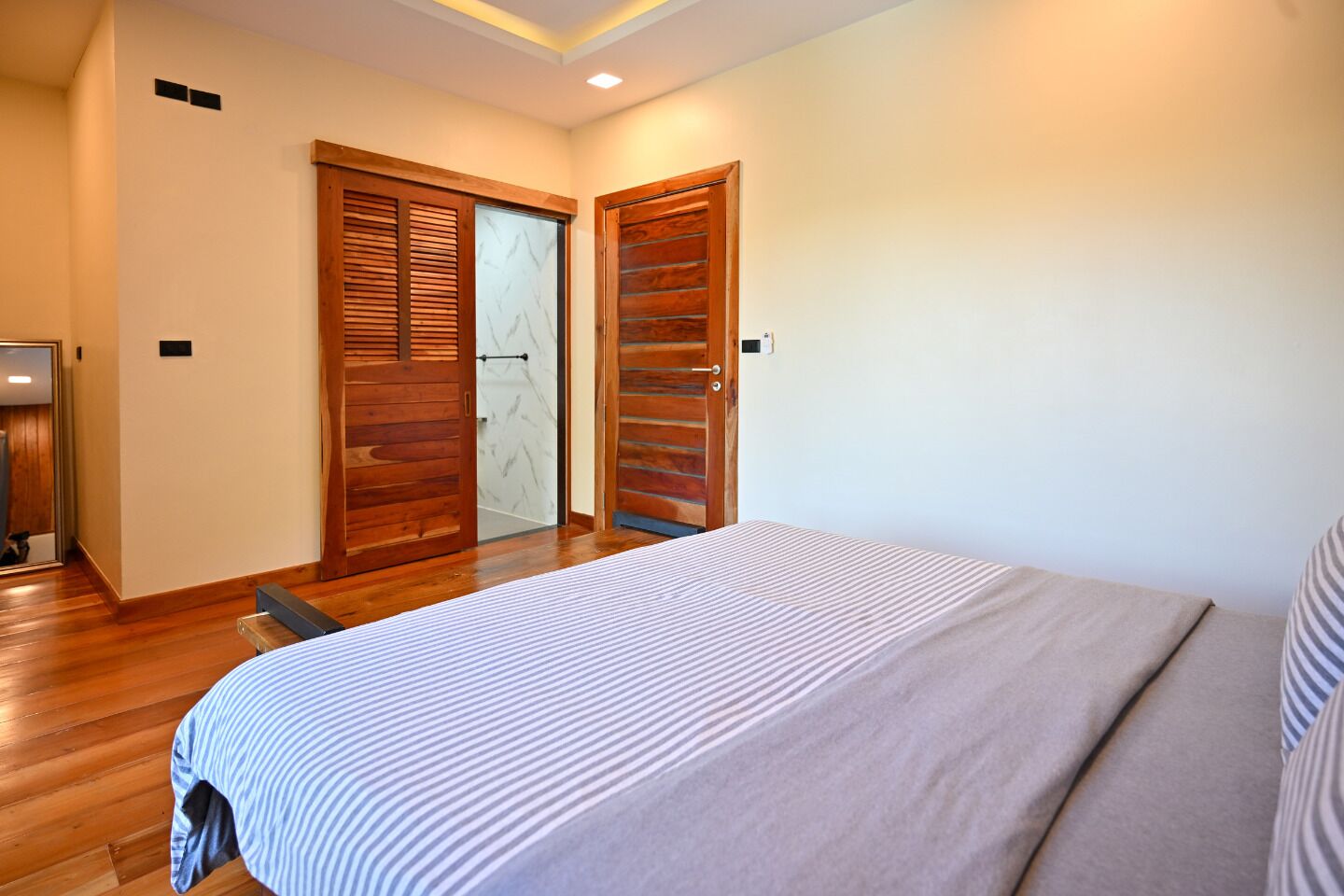 A bedroom with a bed, wooden doors, and a mirror.