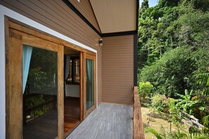 A modern house with a wooden exterior, a sliding glass door leading to a covered outdoor area, and a lush garden. - Moonlight Patong Guesthouse (Patong)