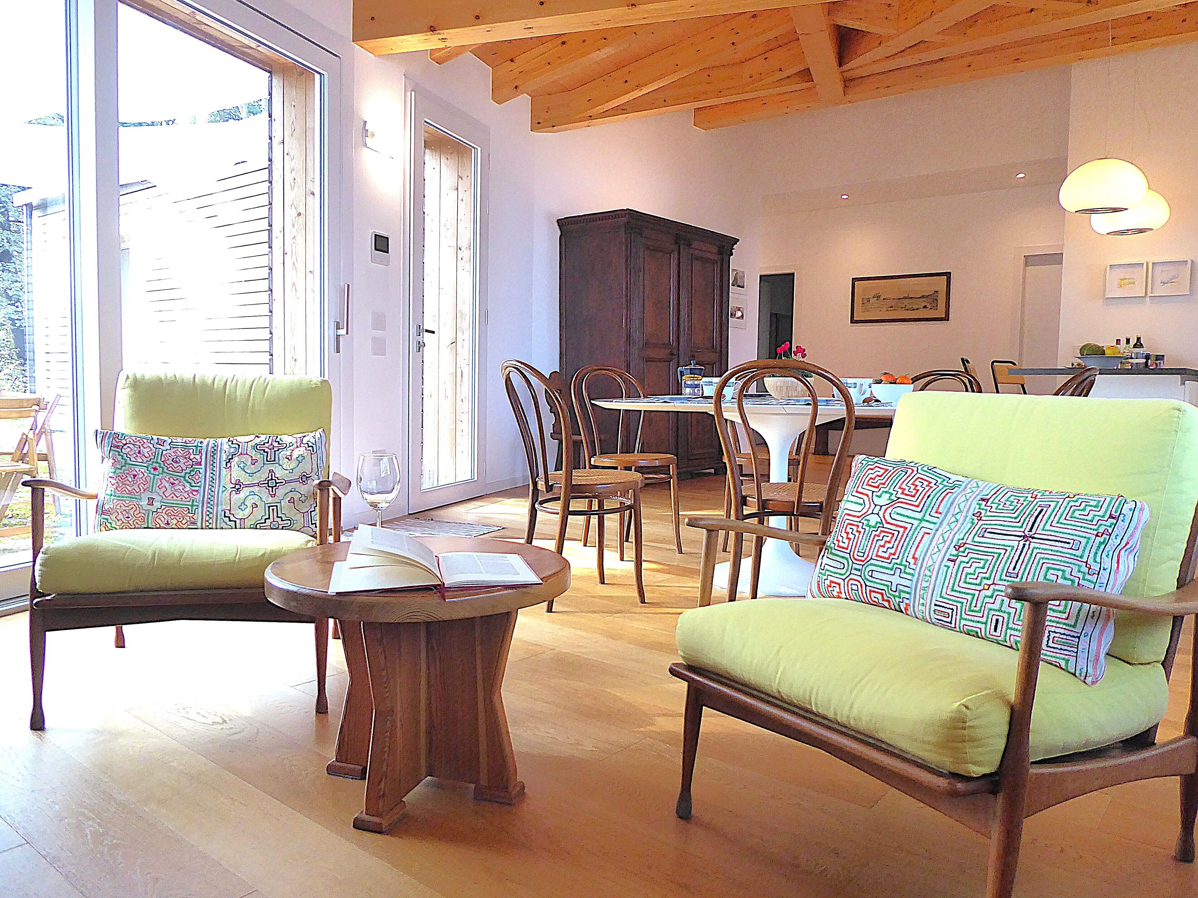 Un salon chaleureux avec des meubles en bois, un coin repas et une cuisine à l’arrière-plan.