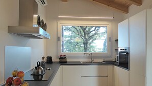 Una cocina moderna con gabinetes blancos, un lavamanos de acero inoxidable y un horno empotrado.