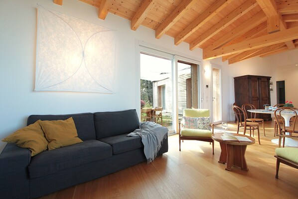 A living room with a dark blue sofa, wooden dining table, and chairs. - Casa Delle Eriche, Colli Euganei, Pool, Wifi (Teolo)