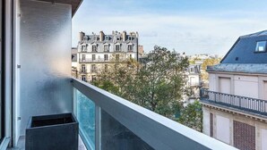 A balcony with a view of classic European architecture, a clear sky, and a metal railing. - AN ICONIC SPACE  IN AN ICONIC LOCATION  - AVENUE RAPP – NEXT TO EIFFEL   (Paris)