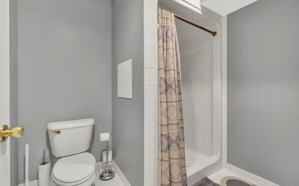 A bathroom with a toilet, a sink, and a shower area with a curtain.