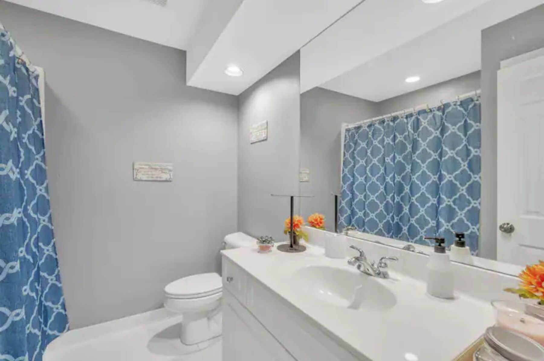 Un baño moderno con un lavamanos blanco, dos grifos, un espejo y un inodoro.