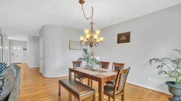 A dining area with a wooden table, chairs, a bench, and a chandelier.