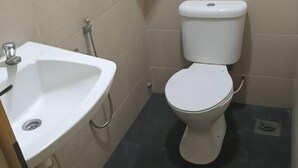 A bathroom with a white sink, toilet, and a shower area.