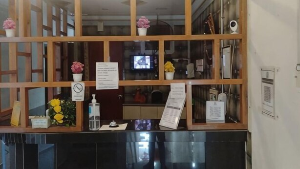 A reception desk with a wooden partition, a television screen, and a menu stand.