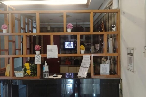 Una reception con un pannello in legno, uno schermo televisivo e un espositore per menu.