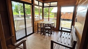 A wooden interior with a dining area, large windows, and a view of the outdoors. - Casa Mango Lepanto #9. Charming 2-bedroom cabin AC, WiFi in enjoyable Lepanto. (Lepanto)