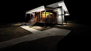 A single-story house with a porch, a staircase leading to the entrance, and a well-lit exterior. - Casa Mango Lepanto #9. Charming 2-bedroom cabin AC, WiFi in enjoyable Lepanto. (Lepanto)