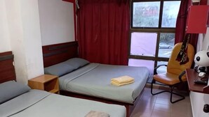 A room with two beds, a chair, a guitar, and a window with curtains. - Evonne Budget Hotel (Tanah Rata)