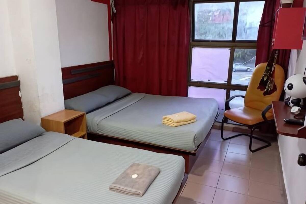 Une chambre avec deux lits, une chaise, une guitare et une fenêtre avec des rideaux.
