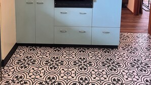 A compact kitchen with a built-in microwave and oven, light blue cabinets, and patterned floor tiles.