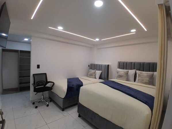A modern bedroom with two beds, a desk, and a chair. - Hotel West Inn (Bogotá)