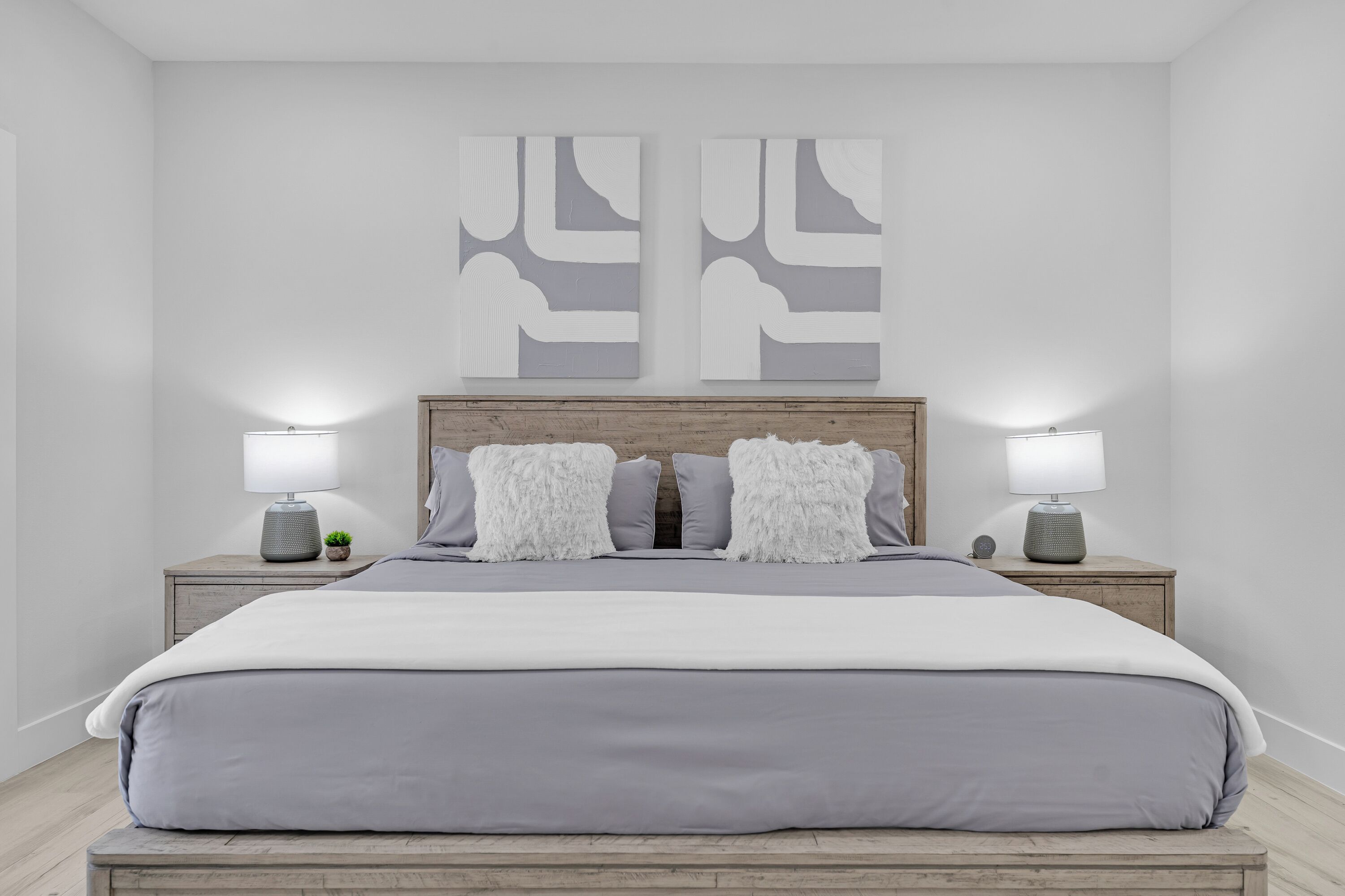 A bedroom with a bed, two bedside tables, and two wall-mounted lamps.