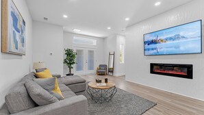 Una sala de estar moderna con un sofá modular, una mesa de centro redonda, un televisor de pantalla plana y una chimenea.