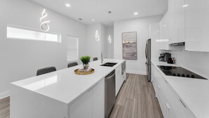 Una cocina moderna con muebles blancos, una isla central y un lavavajillas integrado.