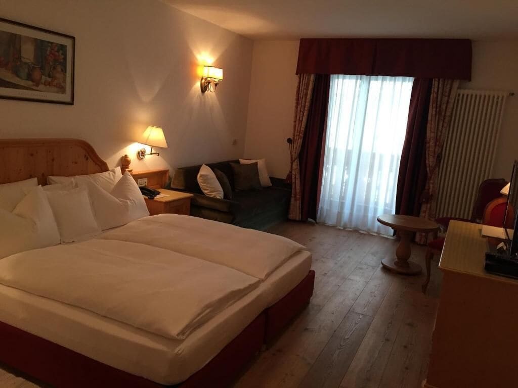 Une chambre d’hôtel avec un grand lit, un canapé, une petite table et une lampe.